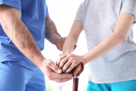 Elderly woman and young man holding hands on walking stick, closeup. Physiotherapy conceptの写真素材