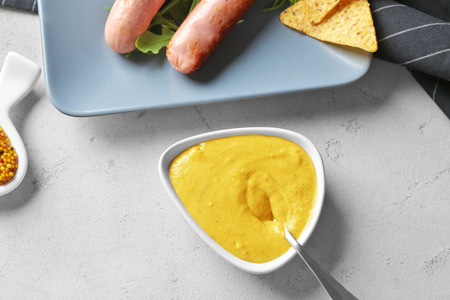 Gravy boat with delicious mustard sauce and spoon on tableの写真素材