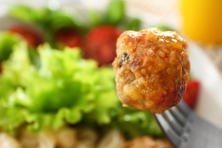 Fork with turkey meatball and plate with tasty meal on backgroundの写真素材