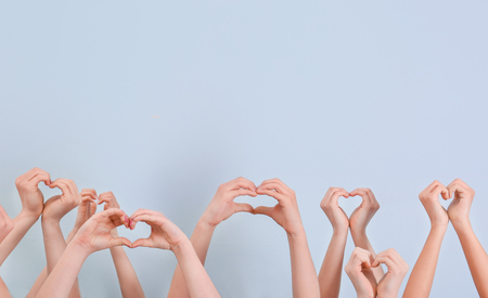 Hearts made by raised hands on light background. Volunteering conceptの写真素材