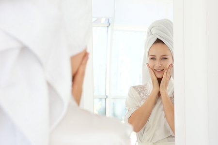 Beautiful young woman after shower near  mirror at homeの写真素材