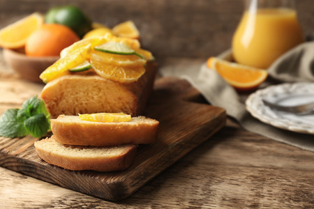 Cutting board with delicious sliced citrus cake and fruits on wooden tableの写真素材