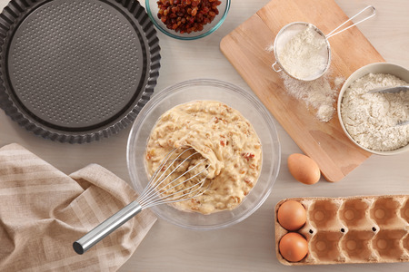 Bowl with raw dough and ingredients on kitchen table