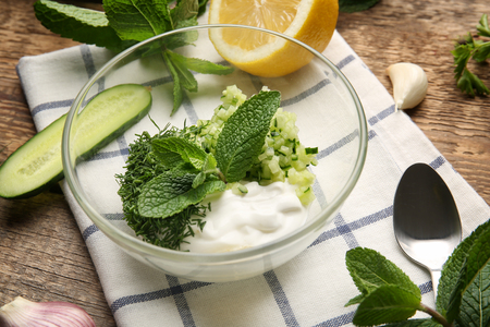 Ingredients and bowl for preparing yogurt sauce on wooden tableの写真素材