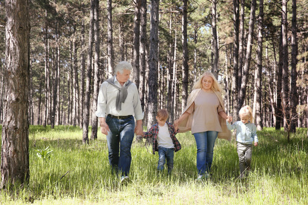Grandparents and children in forest on sunny day