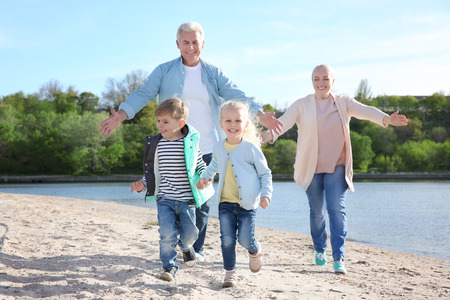 Happy grandparents playing with little children on river bankの写真素材