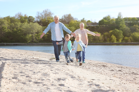 Happy grandparents playing with little children on river bankの写真素材