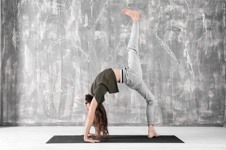 Young man practicing yoga on gray wall backgroundの写真素材
