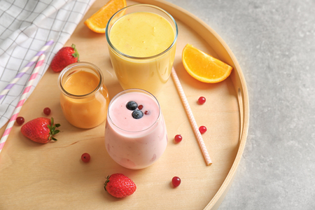 Fresh orange and blueberry yogurt smoothies on wooden trayの写真素材