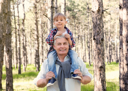 Happy grandfather with little boy in forest on sunny dayの写真素材