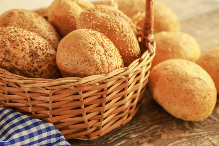 Beautiful composition with wicker basket and delicious bread on wooden tableの写真素材