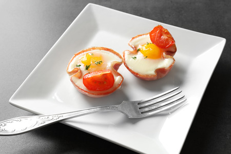 Plate with tasty eggs in ham on tableの写真素材