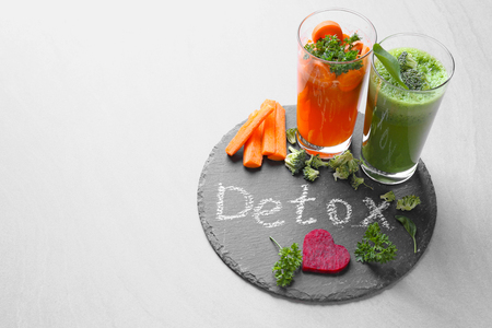 Fresh juices in glasses and ingredients on slate plate with word DETOXの写真素材