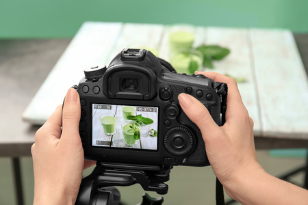 Young woman photographing juice in photo studio, closeup