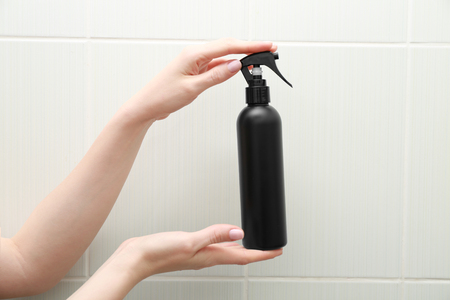 Hands of woman with bottle of cosmetic product in bathroomの写真素材
