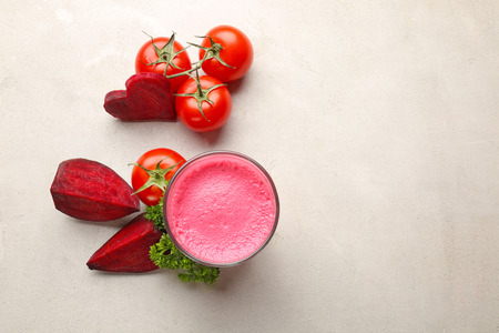 Glass with fresh vegetable juice and ingredients on tableの写真素材