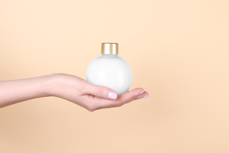 Female hand with bottle of cream for using after shower, on color backgroundの写真素材