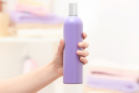 Hand of woman with bottle of cosmetic product in bathroomの写真素材