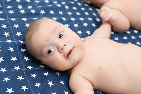 Beautiful baby lying on bed sheetの写真素材