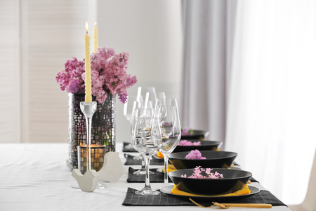Beautiful table setting with black plates and lilac as floral decor