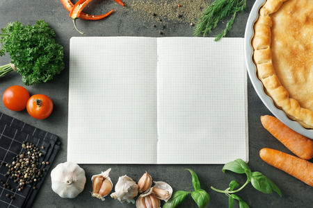 Open notebook and tasty turkey pot pie with ingredients on gray backgroundの写真素材
