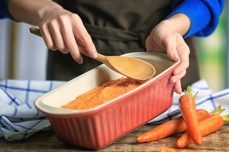 Woman preparing tasty carrot souffle in baking dish