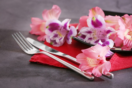 Napkin with cutlery, plate and floral decor on stone table