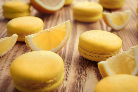 Tasty fresh macarons and lemon slices on wooden table, closeupの写真素材