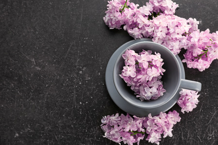 Cup with saucer and lilac floral decor on dark backgroundの写真素材