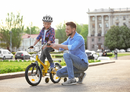 Dad teaching son to ride bicycle outdoorsの写真素材