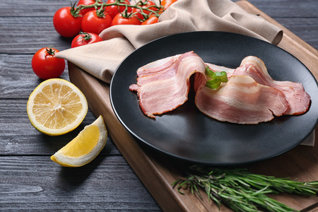 Plate with slices of bacon on wooden boardの写真素材