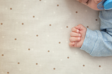 Hand of cute little baby sleeping on bed at home, closeupの写真素材