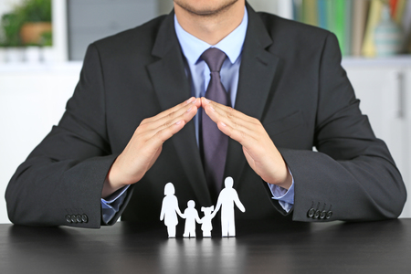 Man covering paper silhouette of family with hands. Insurance conceptの写真素材