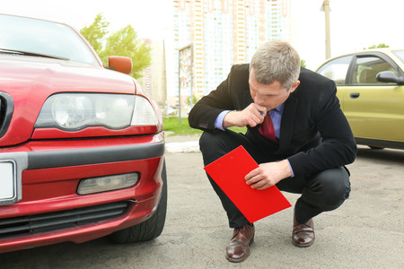 Insurance man checking broken car after accidentの写真素材