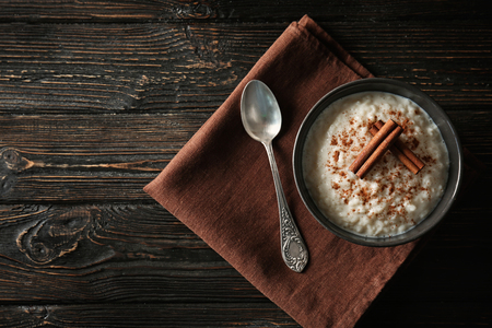 Delicious rice pudding with cinnamon in bowl on wooden backgroundの写真素材