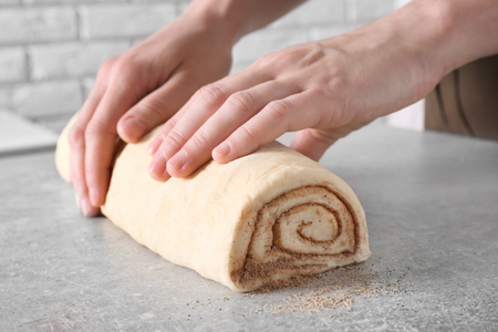 Woman preparing cinnamon roll in kitchenの写真素材