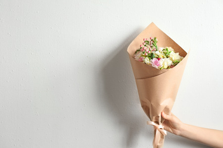 Woman holding beautiful bouquet with freesia on light backgroundの写真素材