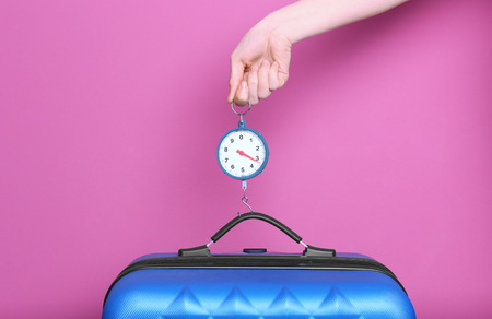 Woman weighting heavy luggage on color backgroundの写真素材