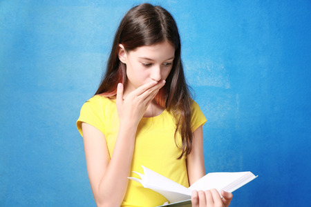 Cute pretty girl with book on color backgroundの写真素材