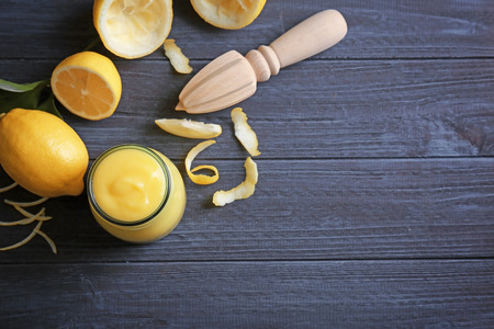 Composition with yummy lemon curd in glass jar on wooden table