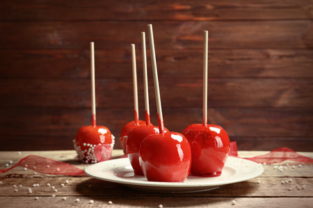 Plate with delicious candy apples on wooden tableの写真素材