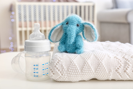 Handmade woolen elephant toy with baby bottle on table