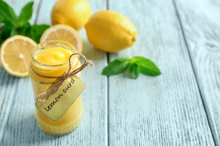 Glass jar with yummy lemon curd on wooden tableの写真素材