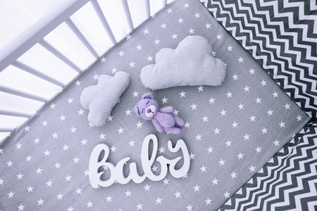 Adorable handmade crochet bear toy with decor and pillows in cribの写真素材