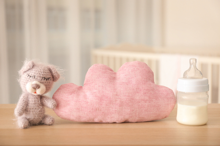 Handmade knitted toy with bottle of milk and pillow on table in bedroomの写真素材