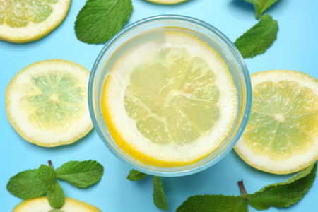 Glass of delicious lemonade on color background