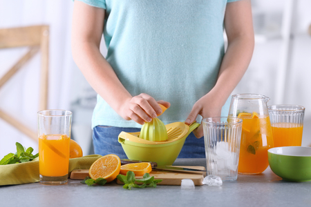 Woman preparing orange lemonade in kitchenの写真素材
