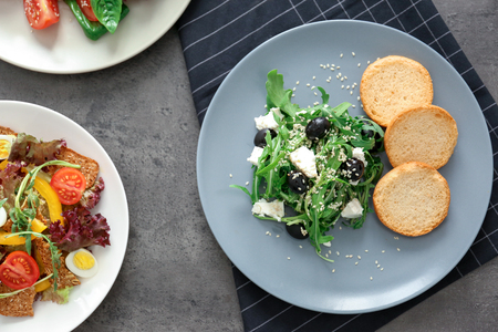 Composition with salad on plates and plaid napkin on grey tableの写真素材
