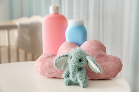 Cute knitted toy elephant and cosmetics for baby on tableの写真素材