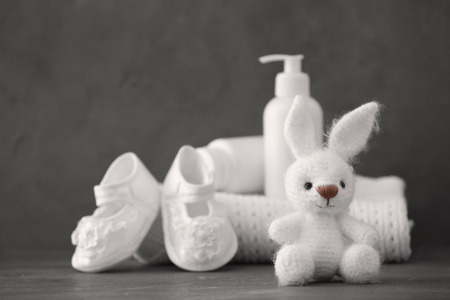 Cute knitted toy bunny and baby accessories on gray backgroundの写真素材